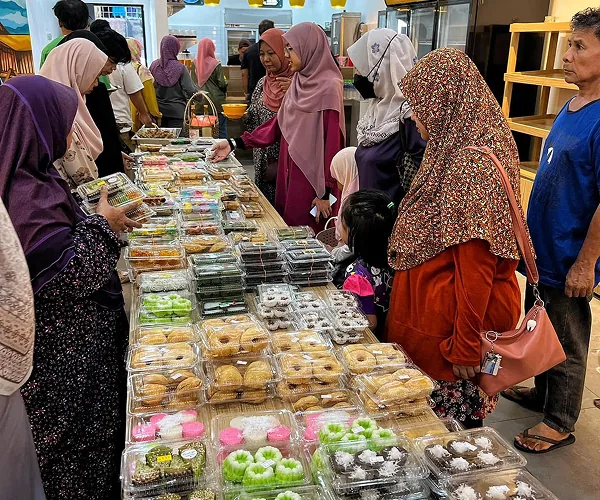 Pelanggan memilih kuih-muih yang tersusun dalam bekas di meja kaunter Mak Kimbong