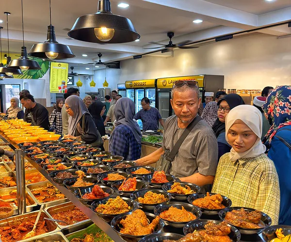 Pelanggan di kaunter lauk Restoran Mak Kimbong, dengan deretan mangkuk lauk