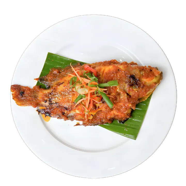 Ikan Talapia Bakar Sambal di atas daun pisang dalam pinggan bulat, dihias hirisan lobak merah dan daun bawang