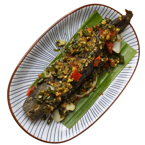 Ikan Keli Belado di atas daun pisang dalam pinggan bujur berjalur, dari menu makan tengah hari Restoran Mak Kimbong